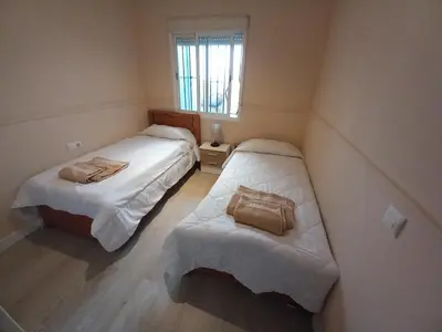 two beds in a small room with a window at Apartamento Centro Estación, Parking Privado in El Puerto de Santa María