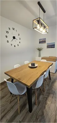 a dining room with a wooden table and a clock on the wall at Casa Plaza Alta in Alcalá de los Gazules