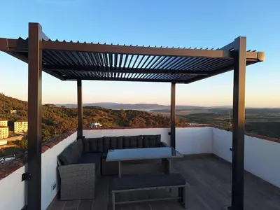 a pergola on a roof with a couch and a table at Casa Plaza Alta in Alcalá de los Gazules