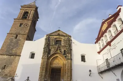 a church with a tower and a clock tower at Casa Plaza Alta in Alcalá de los Gazules