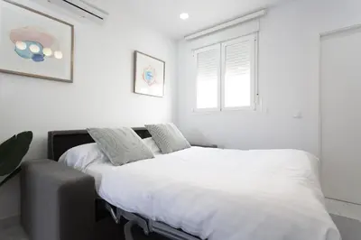 two beds in a white bedroom with a window at BRUJULA ground floor indoor apartment by Cadiz4Rentals in Cádiz