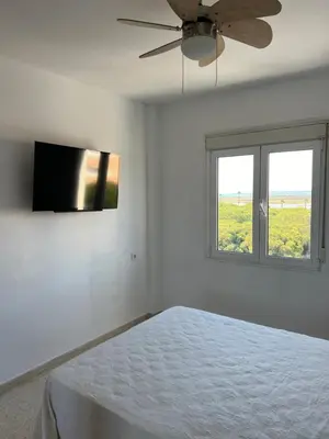 a white bedroom with a bed and a ceiling fan at La Bahía playa in El Trocadero