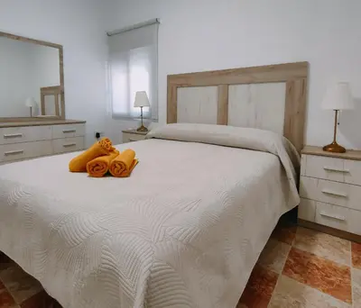 a bedroom with a white bed with two towels on it at Apartamento Playa Tanguillos del Mar in Cádiz