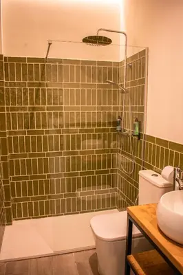 a green tiled bathroom with a toilet and a sink at Apartamentos Ribera del Rio 36 in El Puerto de Santa María
