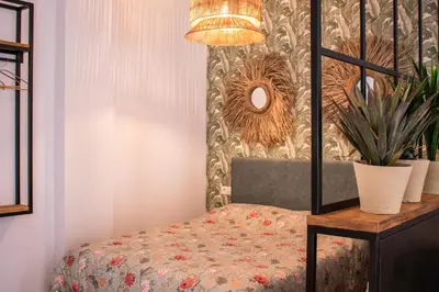 a room with a chair and a table with a lamp at Apartamentos Ribera del Rio 36 in El Puerto de Santa María