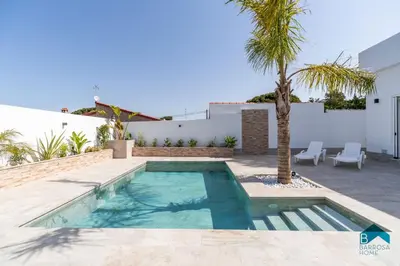 a swimming pool in a backyard with a palm tree at Adosados del Tio Pepe in Chiclana de la Frontera
