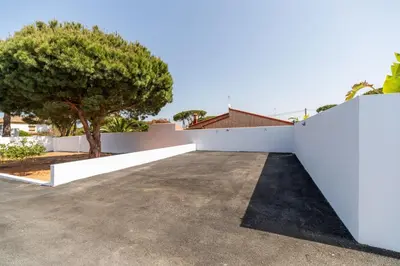 a driveway with a white fence and a tree at Adosados del Tio Pepe in Chiclana de la Frontera