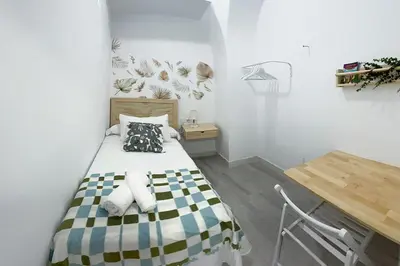 a small bedroom with a bed and a desk at Sanlúcarsun Apartamento en el centro in Sanlúcar de Barrameda