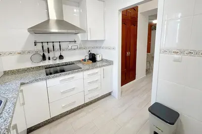 a white kitchen with a sink and a stove at Sanlúcarsun Apartamento en el centro in Sanlúcar de Barrameda