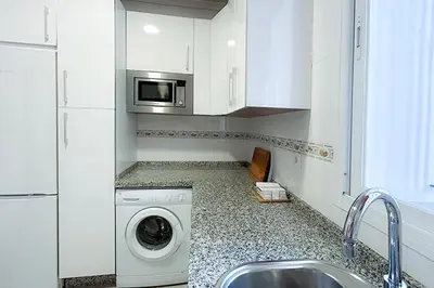 a kitchen with a washing machine and a microwave at Sanlúcarsun Apartamento en el centro in Sanlúcar de Barrameda