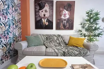 a living room with a couch and portraits of a cat at Sanlúcarsun Apartamento en el centro in Sanlúcar de Barrameda