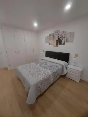 a white bedroom with a bed and a table at Aires de Cadiz Apartamento a estrenar in Cádiz