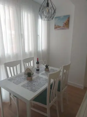 a dining room table and chairs with a white table and aendant light at Aires de Cadiz Apartamento a estrenar in Cádiz