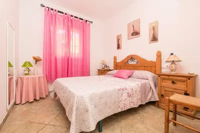 a bedroom with a bed and a pink curtain at La Redondela in Chiclana de la Frontera