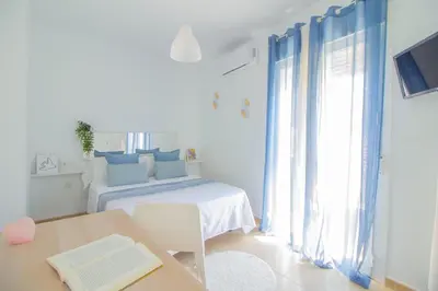 a bedroom with a bed and a table and a window at El paraíso de los Suᴇños in Chiclana de la Frontera
