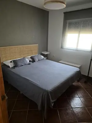 a bedroom with a large bed with a blue blanket at Chalet vacacional in El Puerto de Santa María