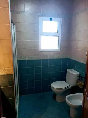 a bathroom with a toilet and a window at Chalet vacacional in El Puerto de Santa María
