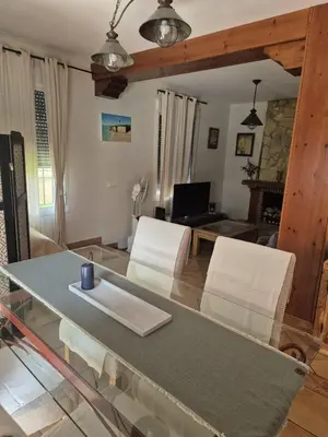 a living room with a glass table and white chairs at Chalet vacacional in El Puerto de Santa María