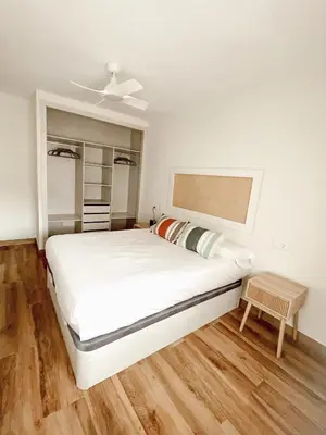 a bedroom with a large white bed and wooden floors at Apartamento Federico Deluxe con Terraza y garaje in El Puerto de Santa María