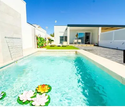 a swimming pool in a house with flowers in the water at Trix I in Chiclana de la Frontera
