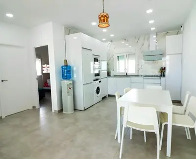 a white kitchen with a white table and chairs at Trix I in Chiclana de la Frontera