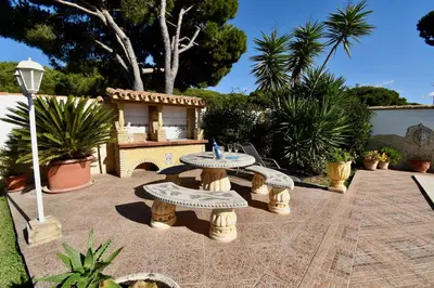a patio with a table and benches in a yard at Del Sol 18 in Chiclana de la Frontera