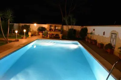a large blue swimming pool in a yard at night at Del Sol 18 in Chiclana de la Frontera