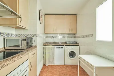a kitchen with a washing machine and a microwave at El Palmeral Ha Free Parking in Cádiz