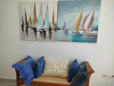 a couch against a wall with a painting of sailboats at Conil Beach View Front House - Espectacular Casa con Vistas al Mar y acceso directo a la Playa in Conil de la Frontera