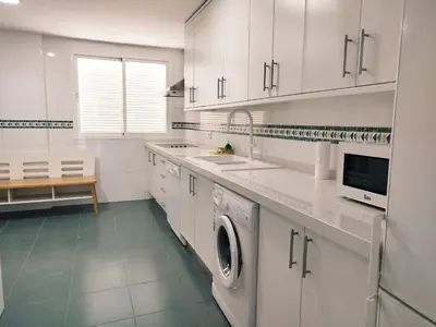 a kitchen with white cabinets and a washer and dryer at Conil Beach View Front House - Espectacular Casa con Vistas al Mar y acceso directo a la Playa in Conil de la Frontera