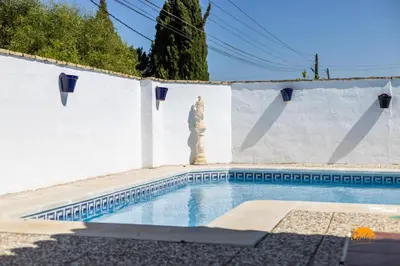 a swimming pool with a statue next to a white wall at Frambuesa by Cádiz Time in Chiclana de la Frontera