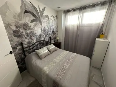 a bedroom with a bed with a painting on the wall at Apartamento Condesa in Sanlúcar de Barrameda