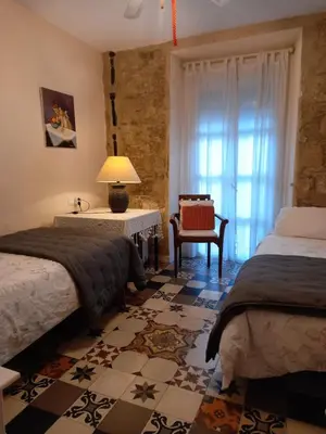 a bedroom with two beds and a chair and a window at El Brujo in Jerez de la Frontera