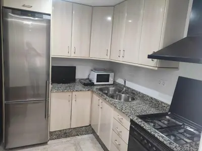 a kitchen with white cabinets and a stainless steel refrigerator at Piso en Cadiz para Verano in Cádiz