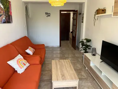 a living room with an orange couch and a coffee table at Piso en Cadiz para Verano in Cádiz
