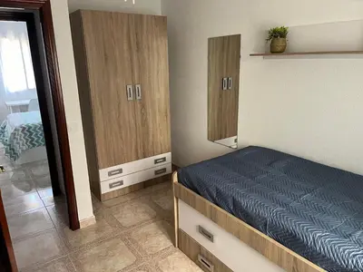 a small bedroom with a bed and wooden cabinets at Piso en Cadiz para Verano in Cádiz