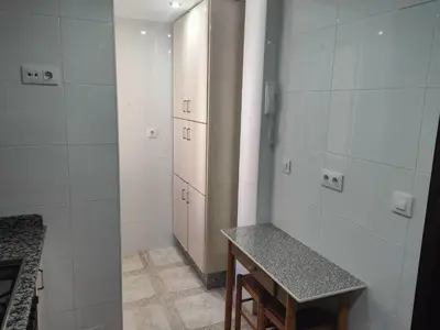 a bathroom with white walls and a table and cabinets at Piso en Cadiz para Verano in Cádiz
