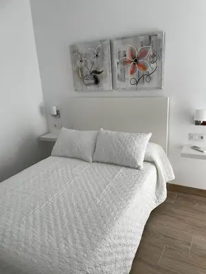 a bedroom with a bed with three pictures on the wall at Apartamento María Sanlúcar con garaje in Sanlúcar de Barrameda