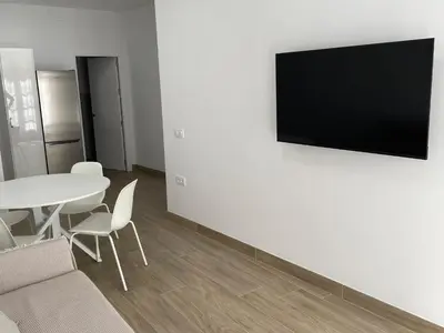 a living room with a table and a television on a wall at Apartamento María Sanlúcar con garaje in Sanlúcar de Barrameda