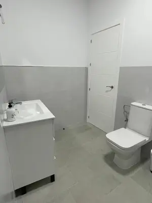 a white bathroom with a toilet and a sink at Apartamento María Sanlúcar con garaje in Sanlúcar de Barrameda
