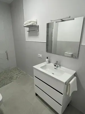 a white bathroom with a sink and a mirror at Apartamento María Sanlúcar con garaje in Sanlúcar de Barrameda
