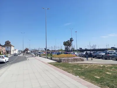 a street with cars parked in a parking lot at La parada in El Puerto de Santa María