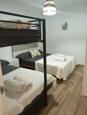 a bedroom with two bunk beds with white sheets at La parada in El Puerto de Santa María