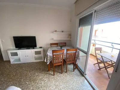 a living room with a table and chairs and a television at Apartamento Centro Chipiona La Perla in Chipiona