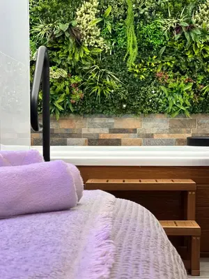 a bed in a room with a wall of plants at BASTINAZO ALOHADREAM - EXCLUSIVO - Design Suite Luxury Love and Spa - Jacuzzi y Sauna Privados in El Puerto de Santa María