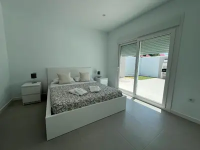 a white bedroom with a bed and a large window at El Nirvana in Chiclana de la Frontera
