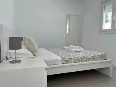 a white bedroom with a bed with a lamp on it at El Nirvana in Chiclana de la Frontera