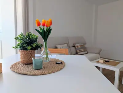 a table with a vase of orange tulips in a living room at Apartamento Costa de la Luz in Chiclana de la Frontera
