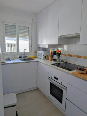 a white kitchen with white cabinets and a sink at Apartamento Costa de la Luz in Chiclana de la Frontera