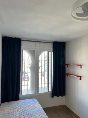 a bedroom with a bed and a window with blue curtains at Casa con encanto El Manatial in El Puerto de Santa María